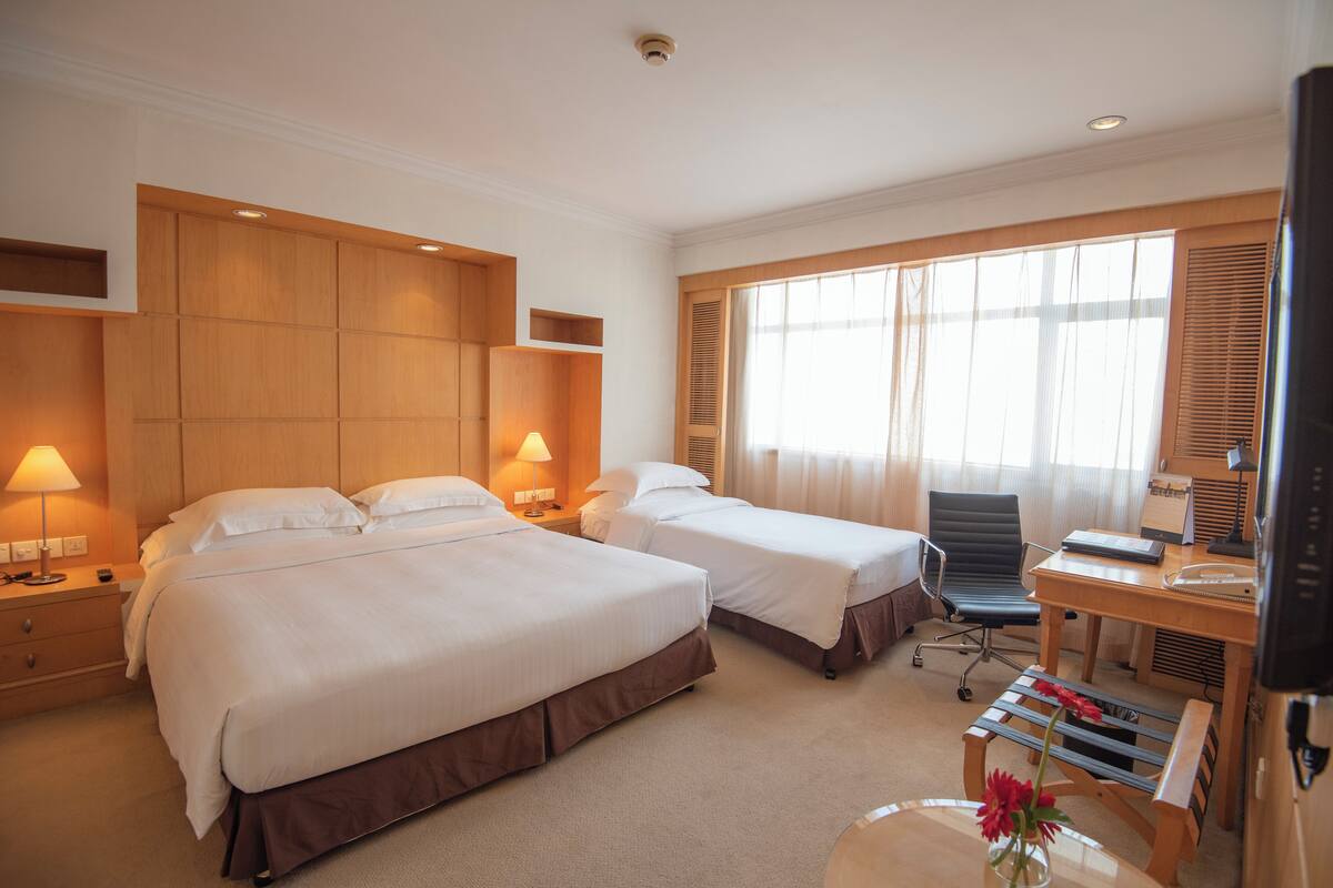 Una habitación de hotel con dos camas, un escritorio, una silla y un televisor.