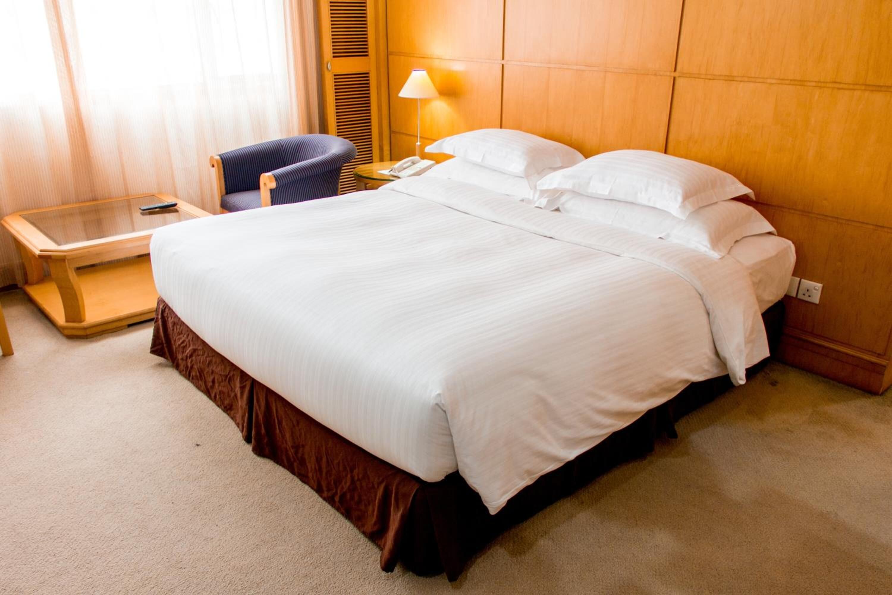 Une chambre d’hôtel avec un grand lit, une table de chevet avec une lampe, une chaise et une petite table avec un téléphone.