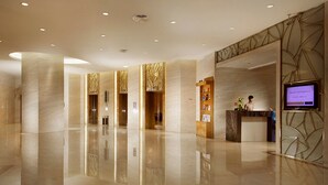 Un moderno vestíbulo de hotel con mostrador de recepción, pantalla digital y piso limpio y pulido.
