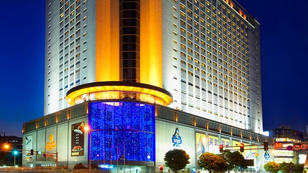 Un hotel alto con una imponente torre de reloj, varios pisos y un amplio vestíbulo.
