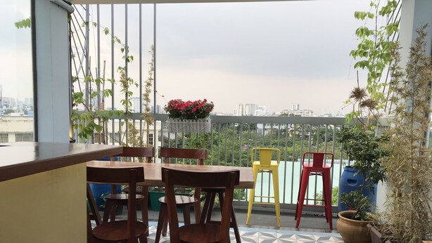 A balcony with a tiled floor, wooden furniture, and potted plants. - Smart Home Group (Ho Chi Minh City)