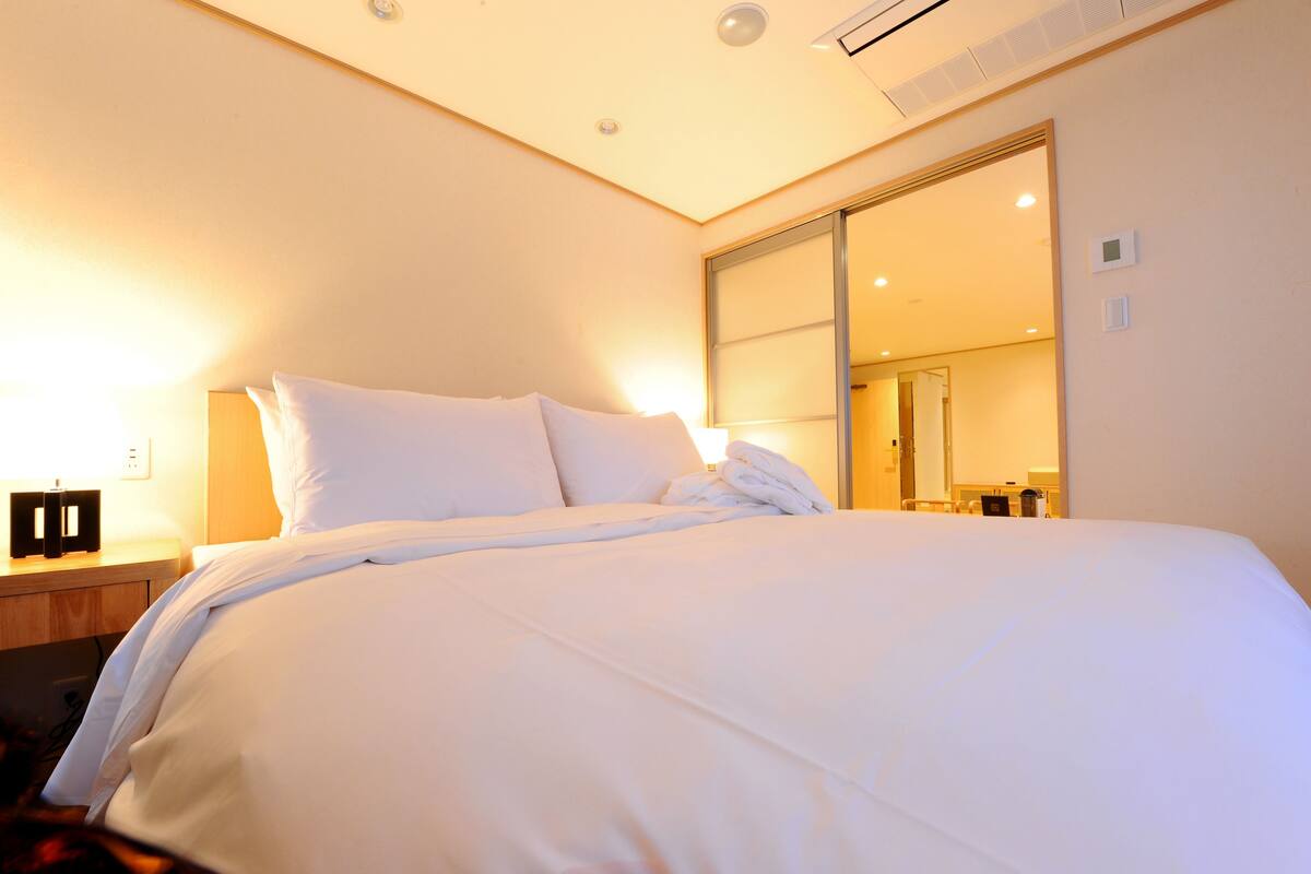 Una cama bien hecha con sábanas blancas en una habitación de hotel.