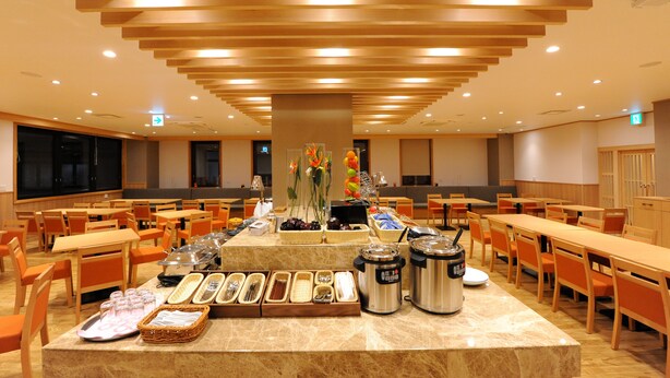 A spacious dining area with multiple tables and chairs, a buffet setup with various food items, and a modern ceiling design. - T Hotel Ryuoo (Yamanouchi)