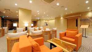 Un moderno vestíbulo de hotel con asientos naranjas, un mostrador de recepción y un atril para música.