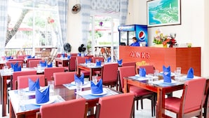 A restaurant with red chairs and tables, a Pepsi refrigerator, and a view of the outdoors. - Zone 5 Boutique Hotel (Da Nang)
