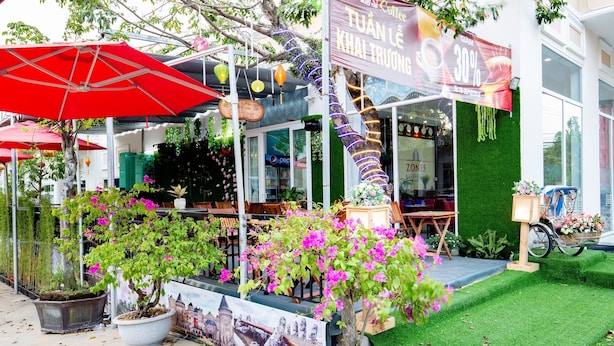 A café with outdoor seating, potted plants, and a promotional banner. - Zone 5 Boutique Hotel (Da Nang)