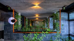 A modern interior with a central planter, wooden beams, and a person tending to plants. - Konoha Boutique Villa (Da Nang)
