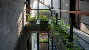 A modern interior with concrete walls, wooden beams, and a staircase leading to an upper level. - Konoha Boutique Villa (Da Nang)