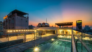 A rooftop pool area with a glass balustrade, a covered seating area, and a building with a rooftop pool. - Konoha Boutique Villa (Da Nang)