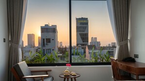 A hotel room with a large window, a bed, a desk, and a chair. - Konoha Boutique Villa (Da Nang)