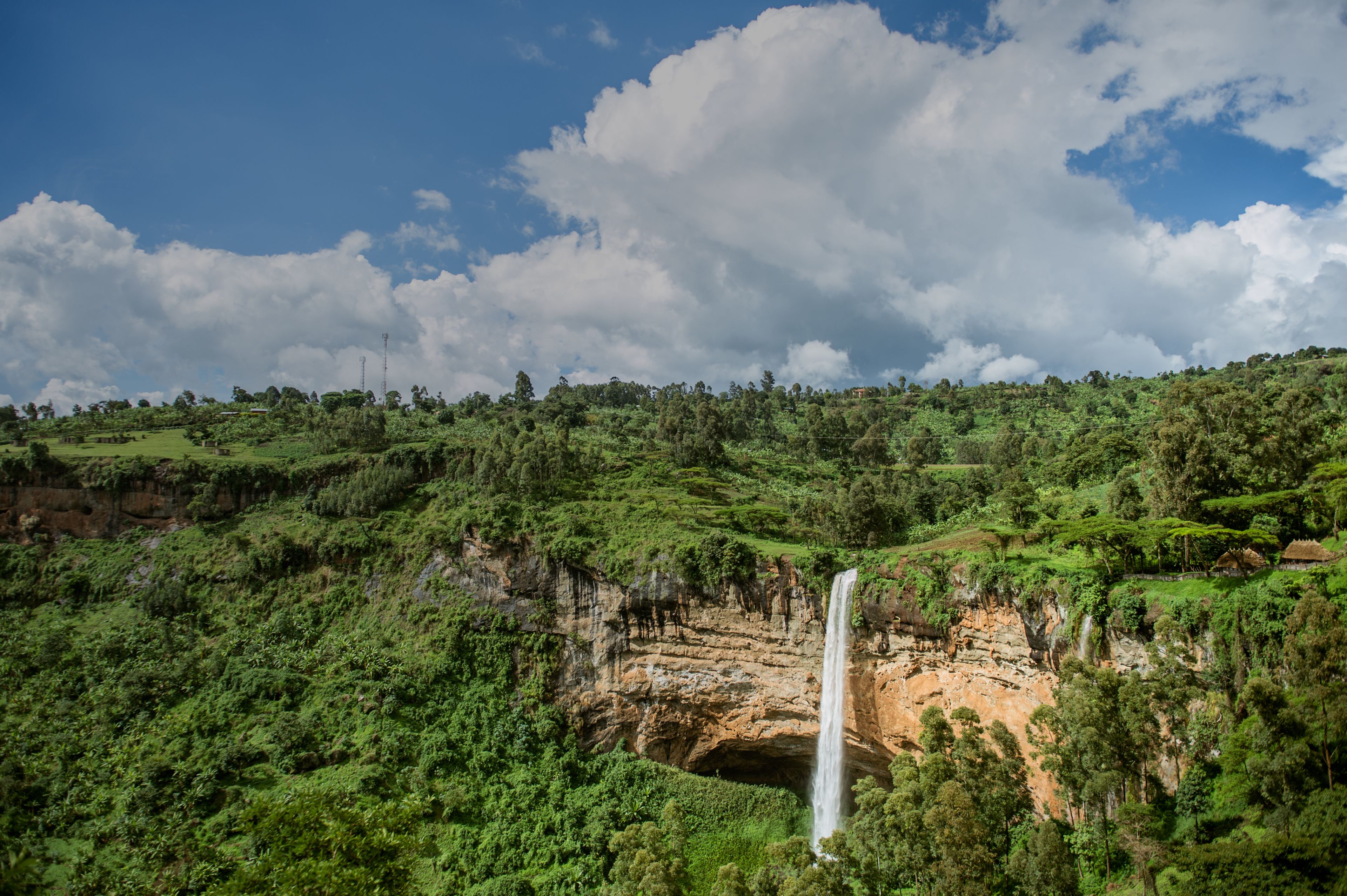 Paisagem verdejante com uma cascata descendo por um penhasco.
