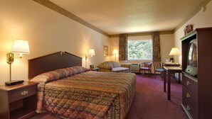 A hotel room with a large bed, two bedside tables with lamps, a desk with a chair, a television, and a window with curtains. - Knights Inn Salem (Salem)