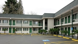 A motel with a parking lot, green doors, and a covered walkway. - Knights Inn Salem (Salem)