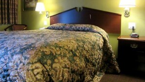 A hotel room with a bed, two bedside lamps, a nightstand, and a chair. - Knights Inn Salem (Salem)