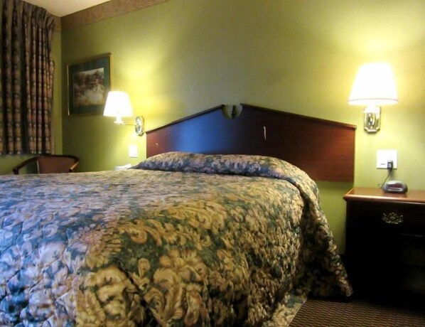 A hotel room with a bed, two bedside lamps, a nightstand, and a chair. - Knights Inn Salem (Salem)