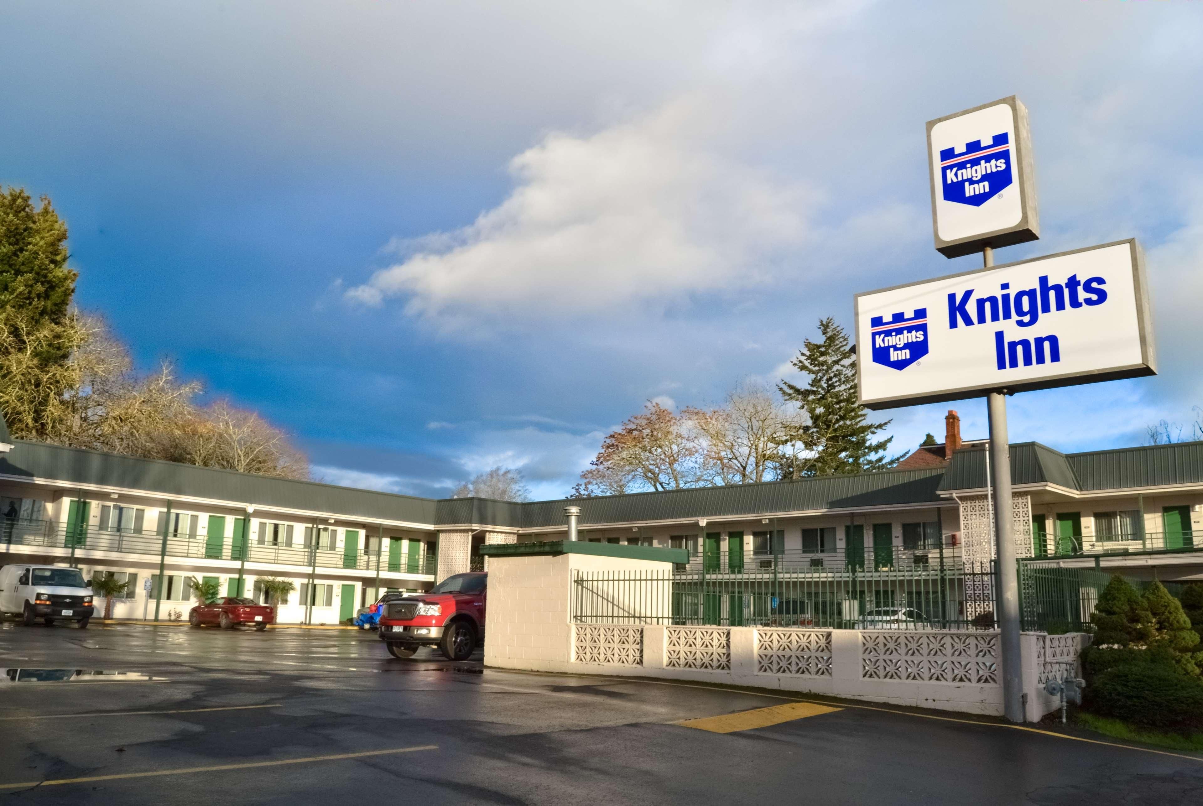Um Knights Inn com estacionamento e um edifício com persianas verdes.