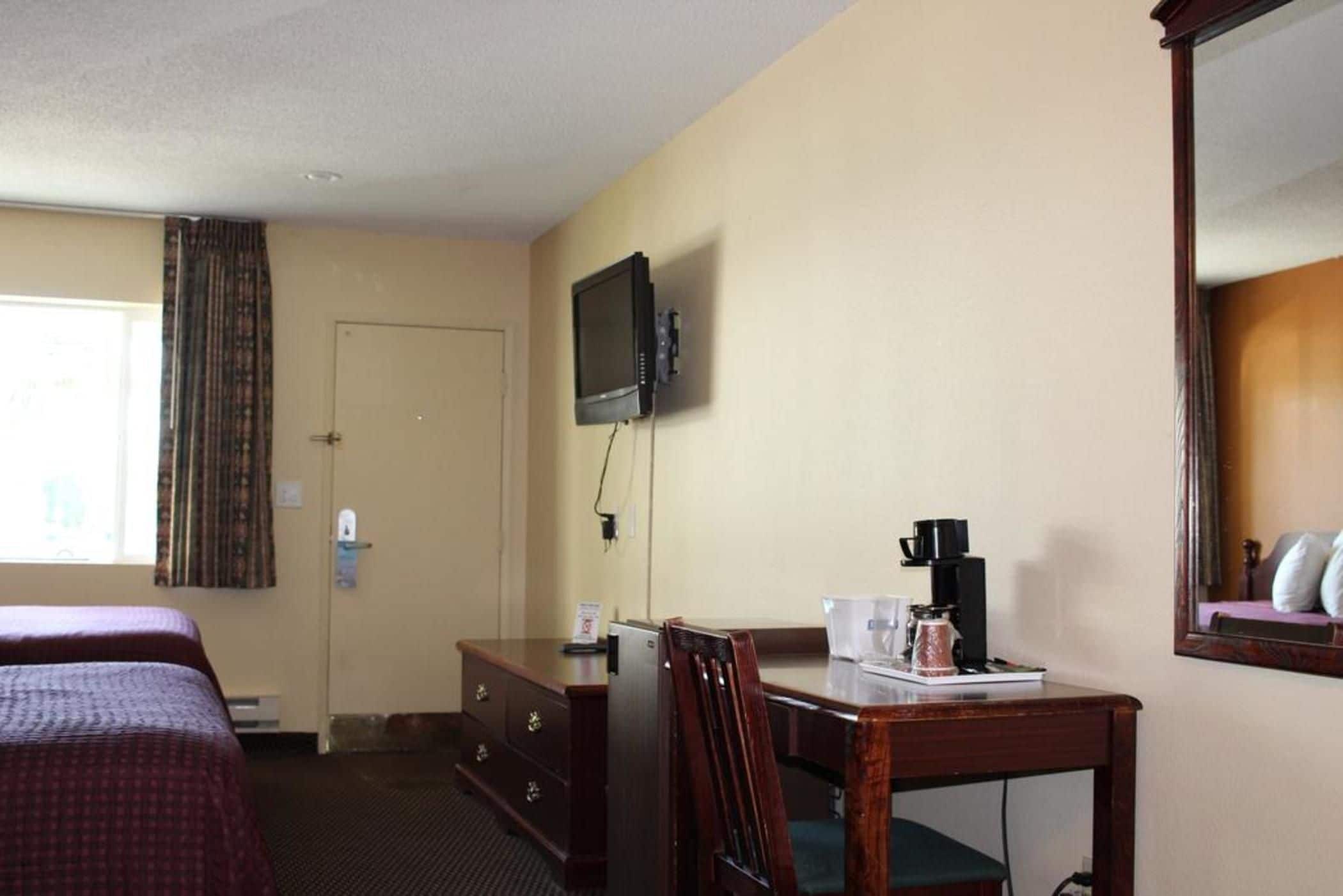 Une chambre d’hôtel avec deux lits, un bureau avec une machine à café, une télévision et un miroir.