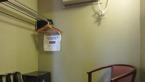 A hotel room with a single wooden chair, a coat rack with hangers, and a sign on the wall. - Knights Inn Salem (Salem)
