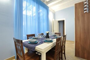 A dining area with a table set for four, chairs, a wooden door, and a blue curtain.