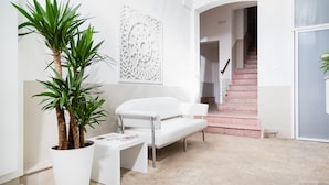 Un interior moderno con un sofá blanco, una planta en maceta y un elemento decorativo en la pared.