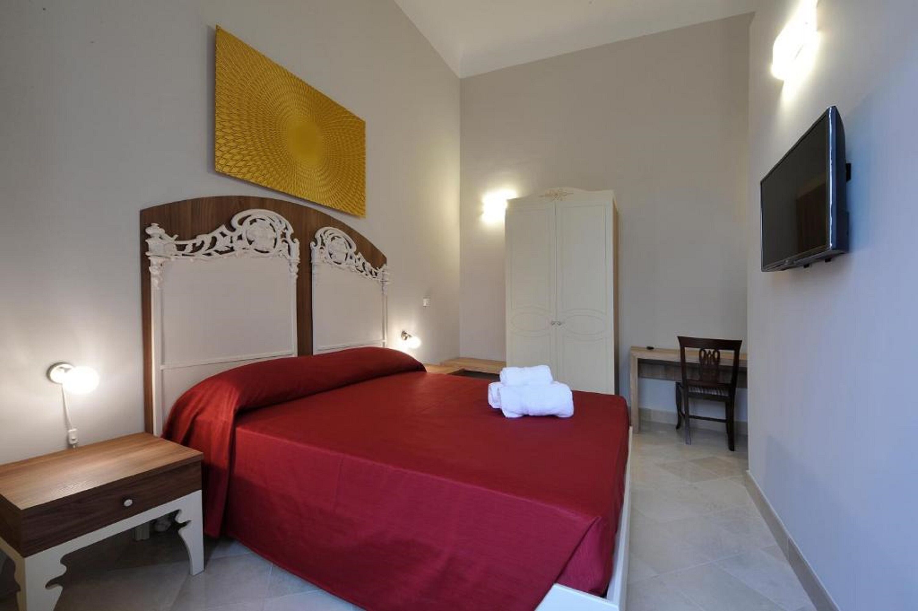 A neatly arranged bedroom with a large bed, a bedside table, a wardrobe, and a television mounted on the wall.