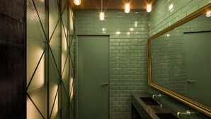 A restroom with green tiled walls, a large mirror, and three sinks. - The Bridge Wroclaw - MGallery (Wroclaw)