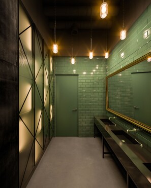 A restroom with green tiled walls, a large mirror, and three sinks. - The Bridge Wroclaw - MGallery (Wroclaw)
