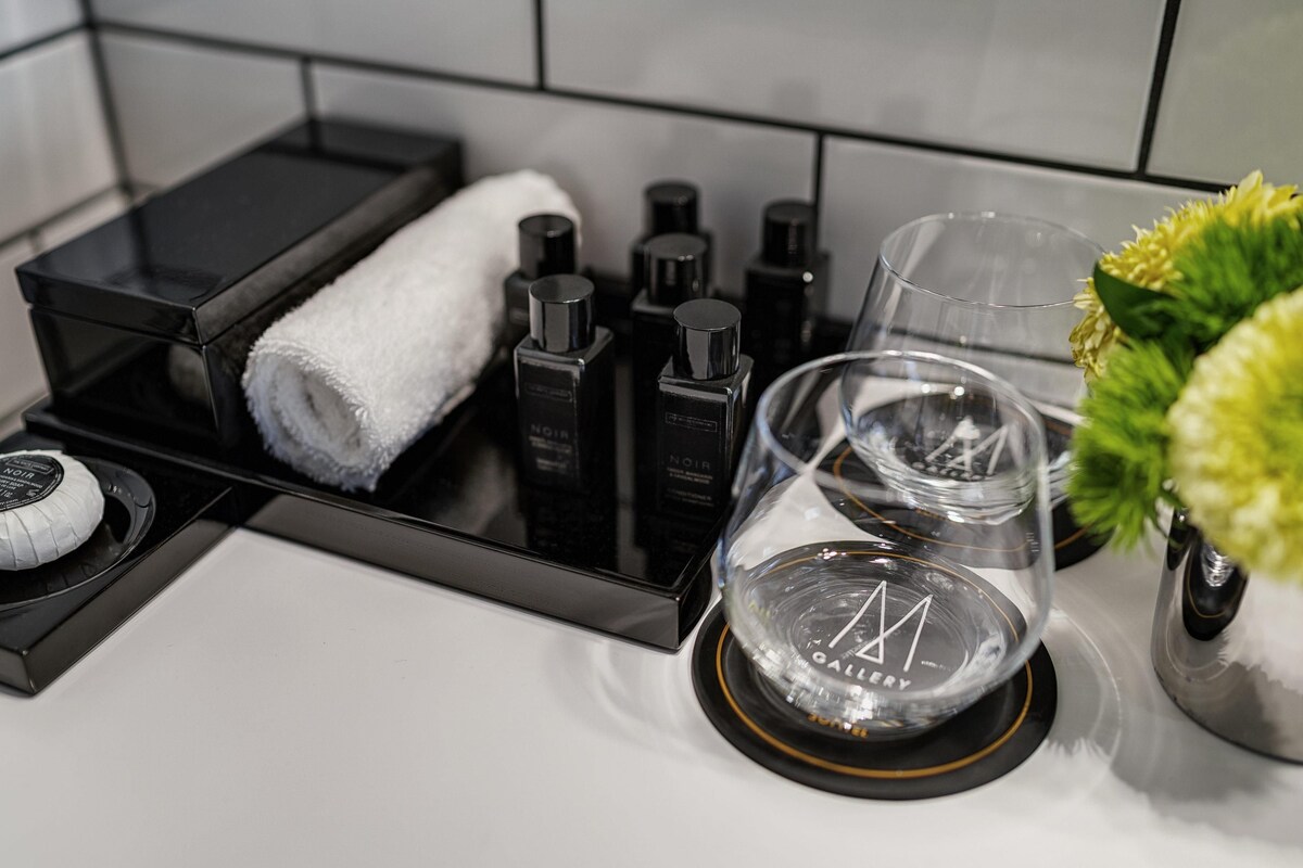 A bathroom counter with a black tray holding a white towel, a glass, and toiletries.