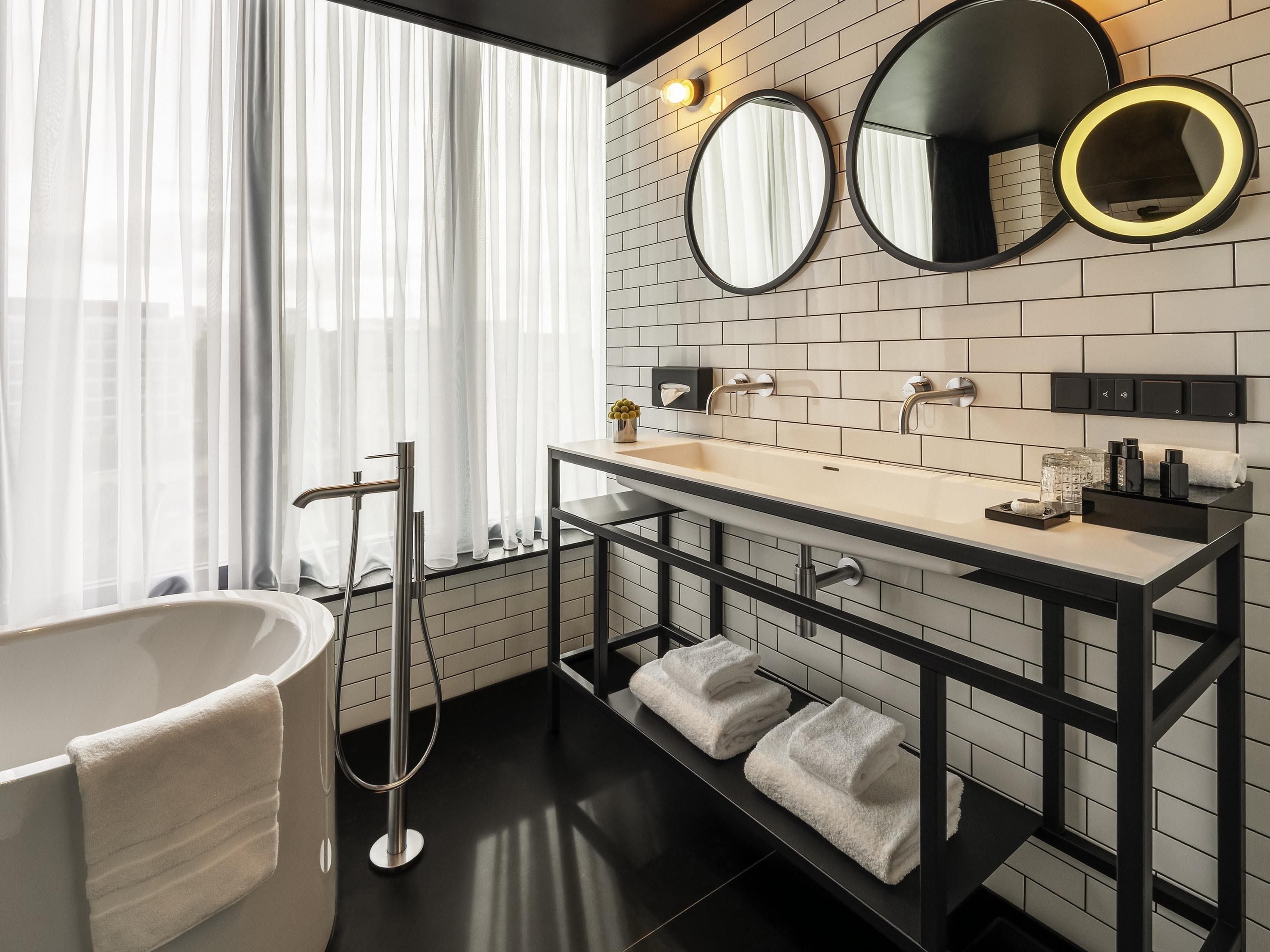 A modern bathroom with a freestanding bathtub, a vanity with a mirror, and a towel rack.