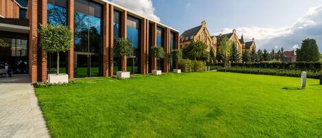 A modern building with large glass windows, a brick facade, and a well-maintained lawn.