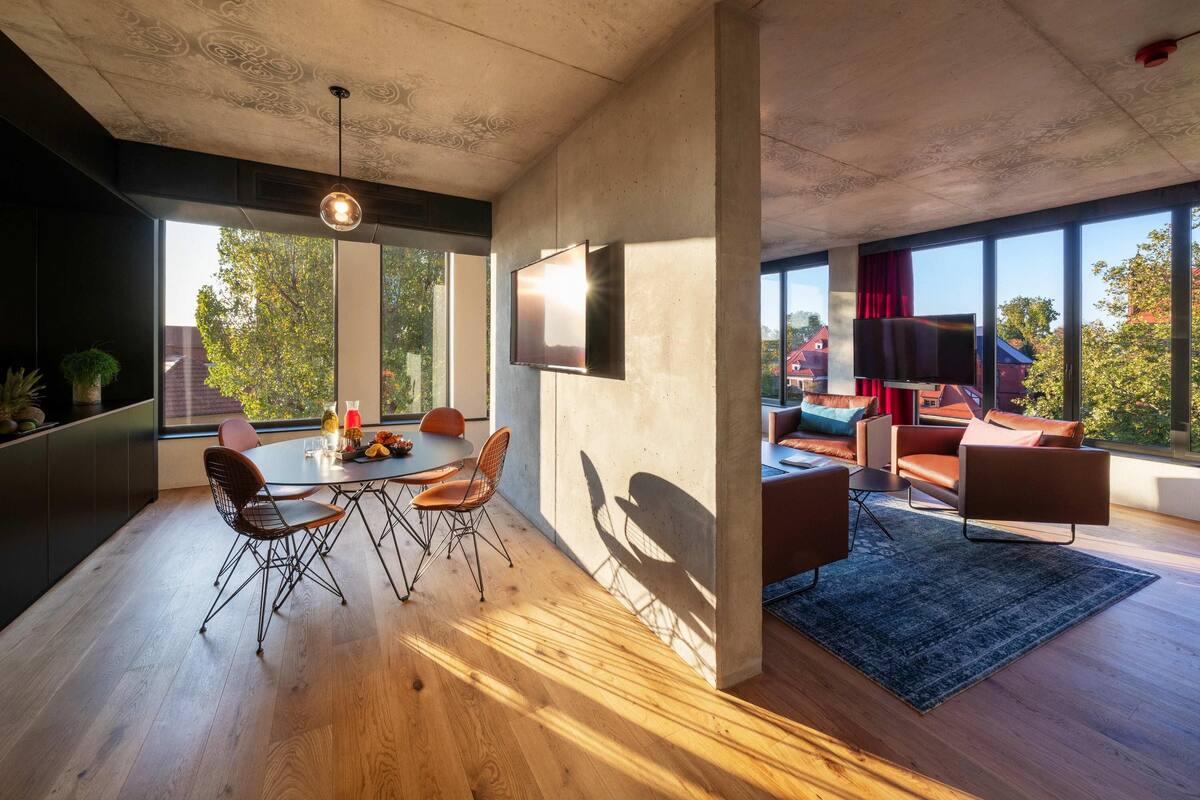A modern living room with a dining area, large windows, and a flat-screen TV.