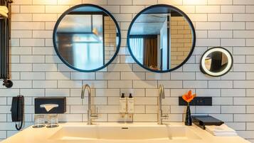 A bathroom with two round mirrors, a white sink, and a towel rack.