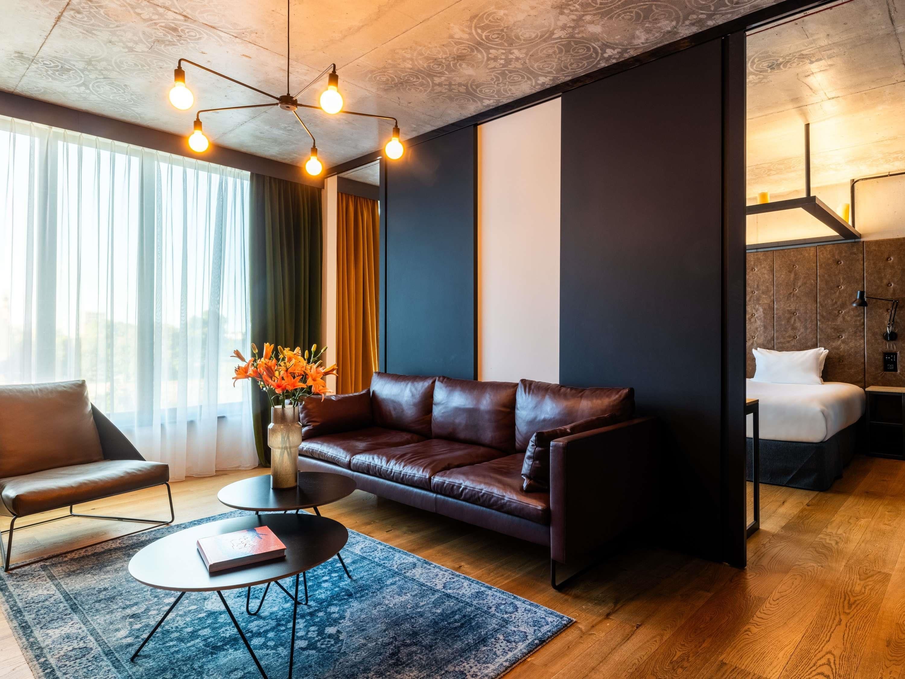 A modern living room with a leather sofa, a coffee table, and a vase of flowers.