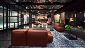 A spacious lobby with leather seating, a coffee table, and a potted plant. - The Bridge Wroclaw - MGallery (Wroclaw)