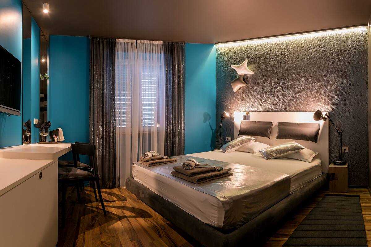 A modern hotel room with a large bed, a desk, and a shower area.