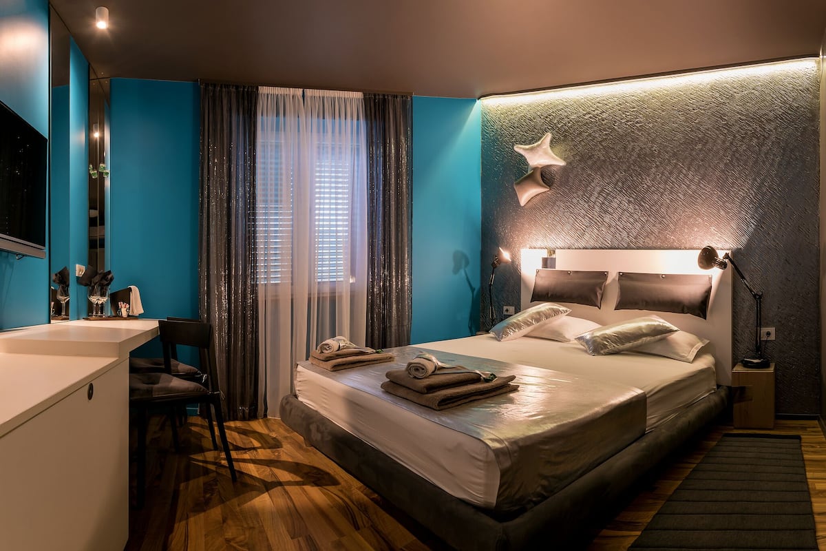 A modern hotel room with a large bed, a desk, and a shower area.