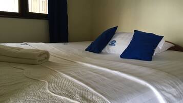 A hotel room with a bed, pillows, and a folded towel.