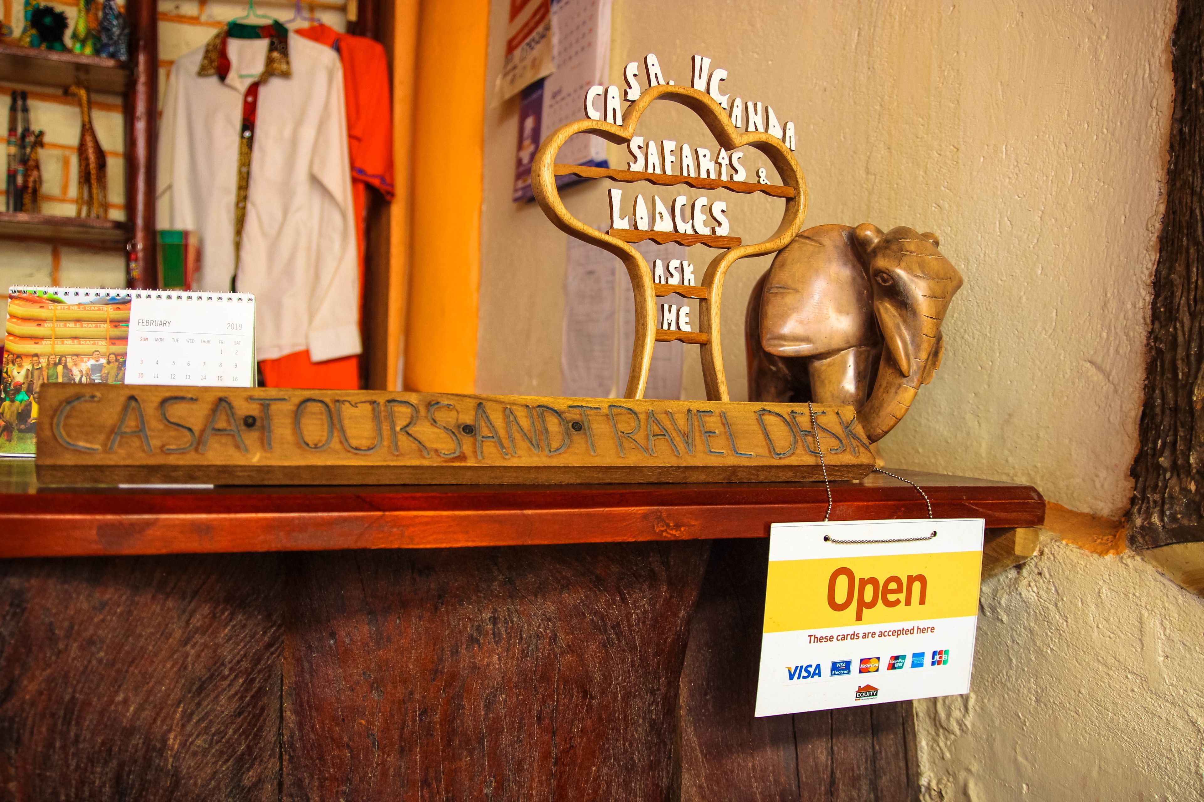 Un letrero de madera que dice "CASA TOURS AND TRAVEL DESK" y una cabeza de elefante de bronce.