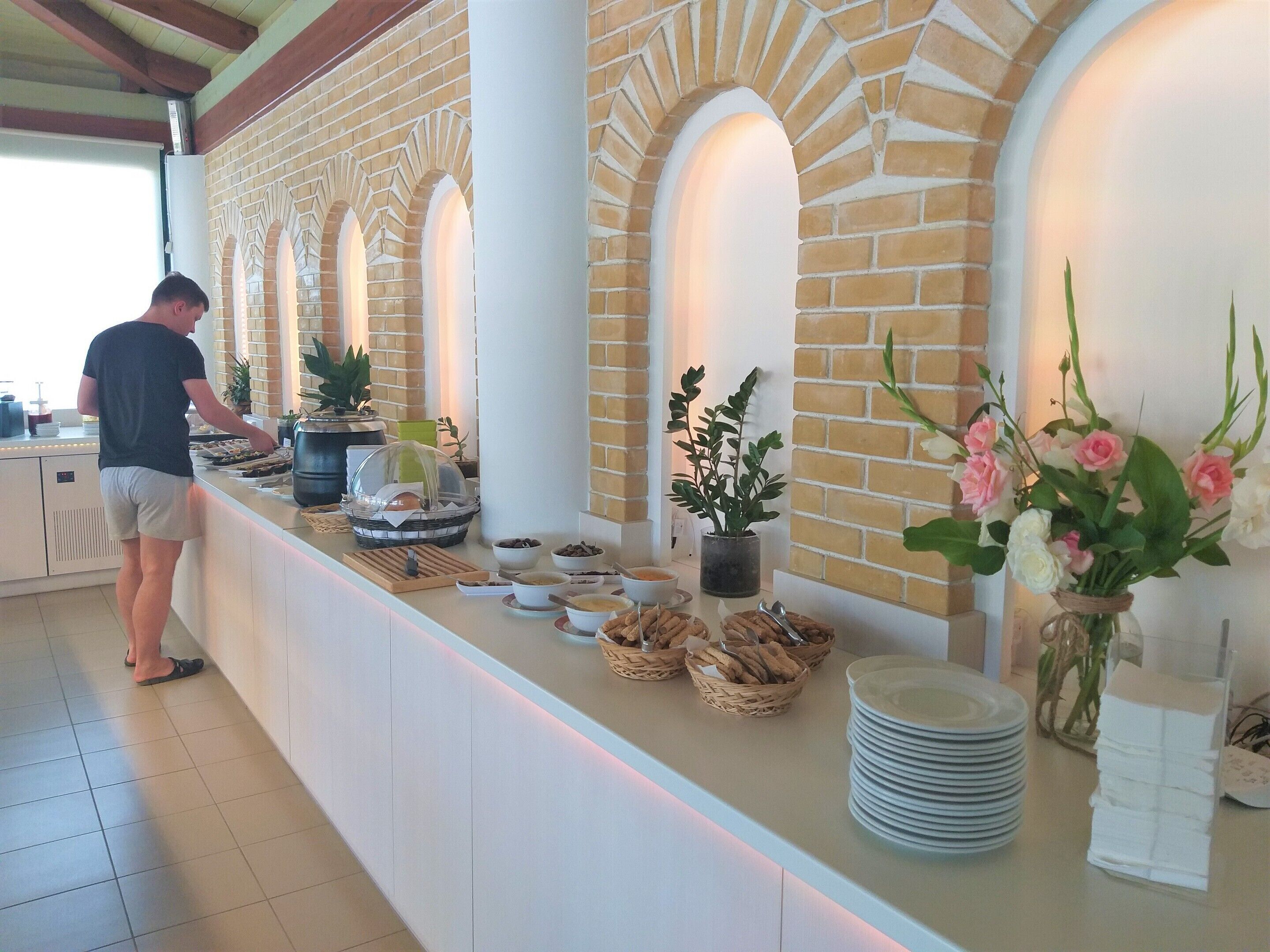 A buffet setup with various food items and a person serving.