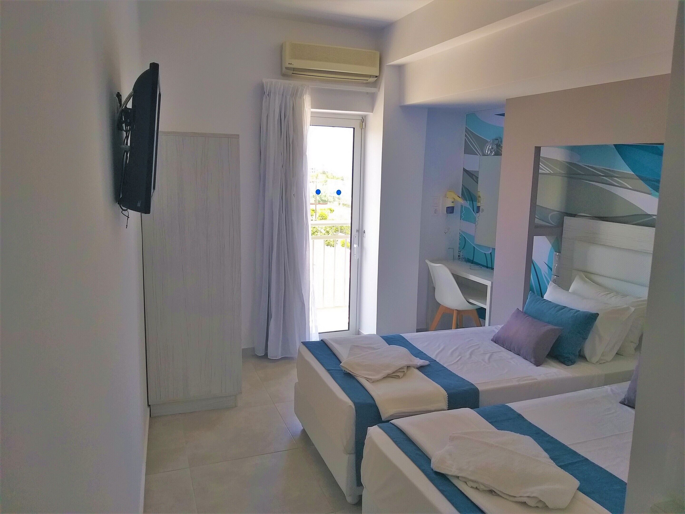 Een hotelkamer met twee bedden, een bureau en een raam met gordijnen.