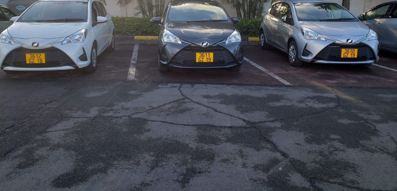 Un estacionamiento con tres coches aparcados en fila.