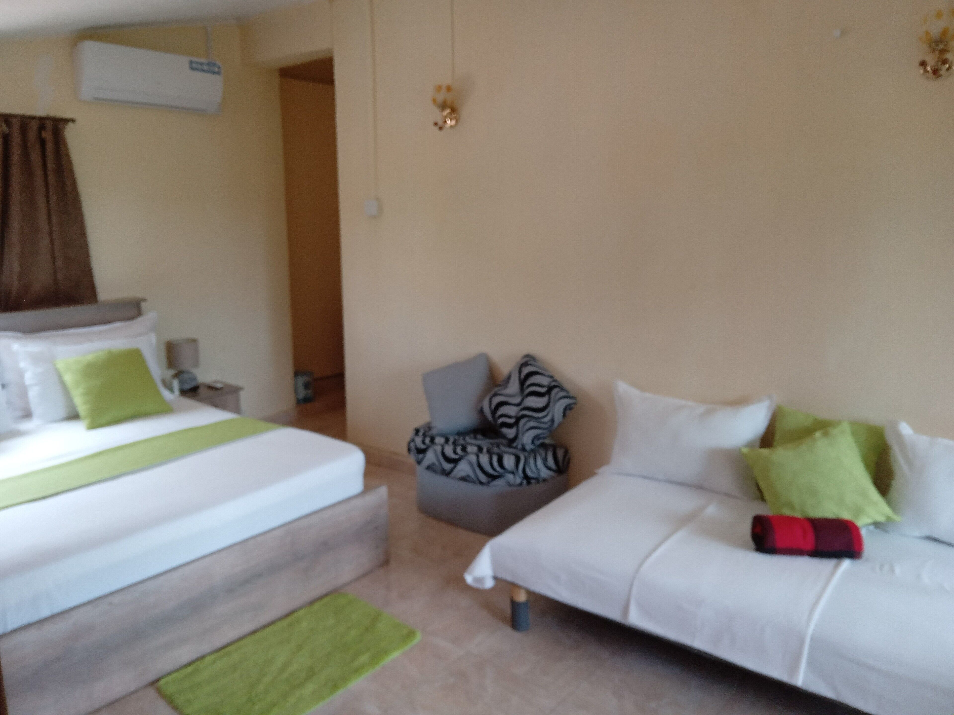Un dormitorio con cama, sofá, silla y alfombra verde.