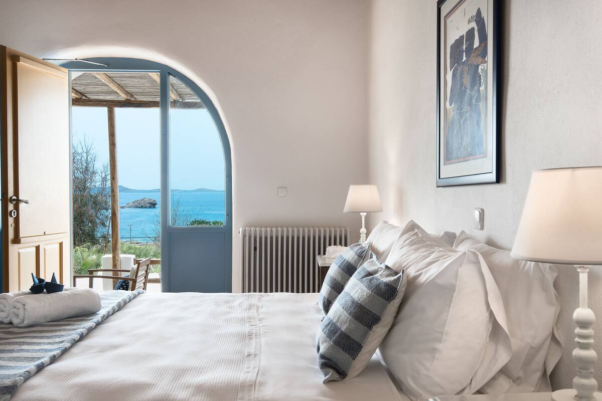 Un dormitorio con una cama grande, vistas al mar y una puerta que da a un espacio exterior.