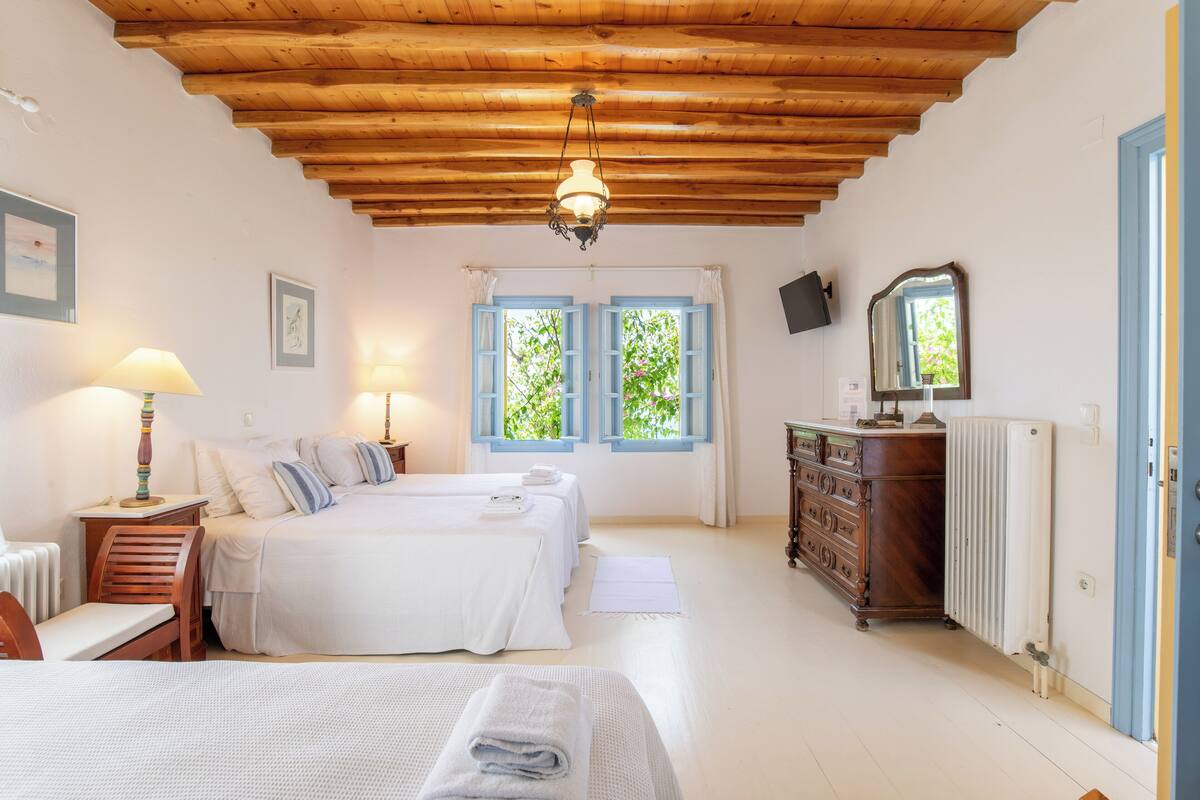 Un dormitorio con dos camas, techo de madera, cómoda y espejo.