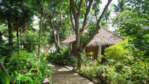 A paved pathway leading to a thatched-roof structure surrounded by lush greenery. - Mandala Spa and Resort Villas (Boracay Island)