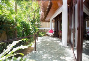 A stone-paved pathway leading to a seating area with a chair and a table, surrounded by lush greenery and a bamboo structure. - Mandala Spa and Resort Villas (Boracay Island)