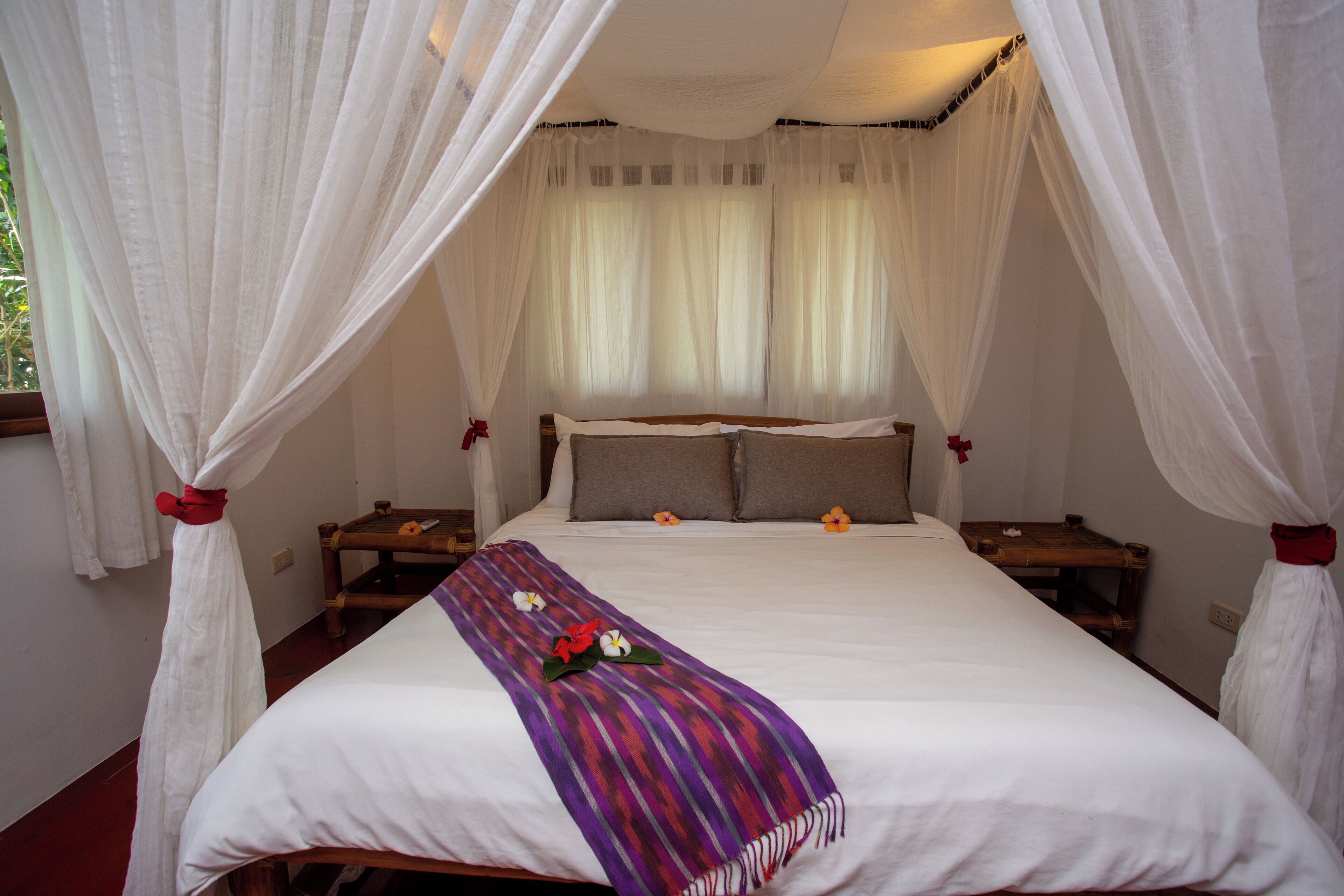 Een bed met hemelbed, kussens en een decoratieve plaid.