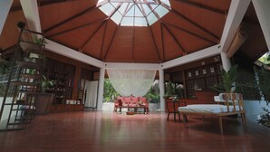 A spacious room with a high ceiling and a skylight, featuring a wooden bench, a bed, and a sofa. - Mandala Spa and Resort Villas (Boracay Island)