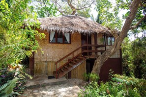 A rustic thatched-roof house with a wooden staircase leading to a door, surrounded by lush greenery. - Mandala Spa and Resort Villas (Boracay Island)
