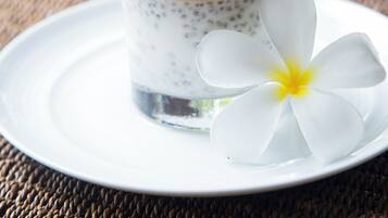 Un postre en un vaso con una flor blanca sobre un plato.